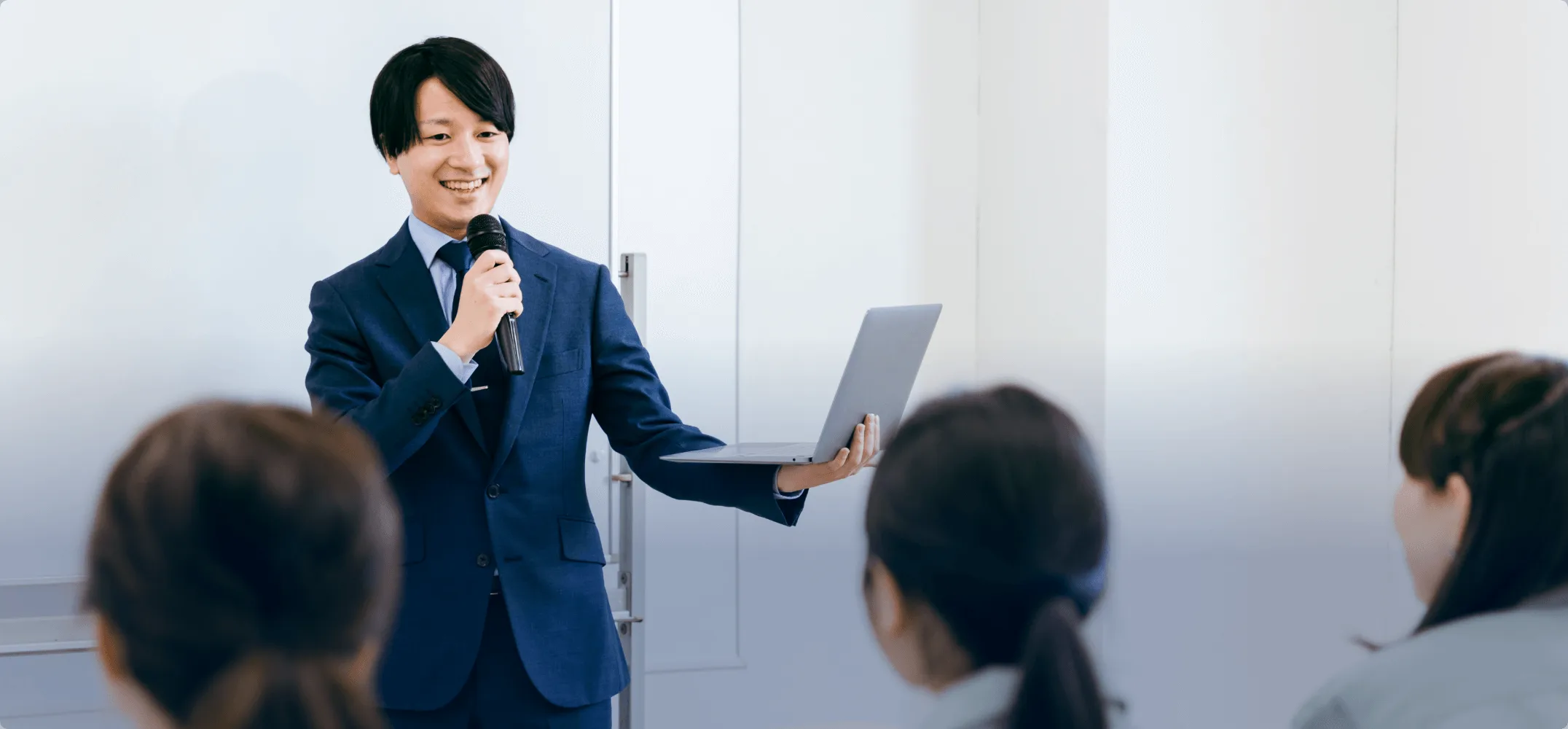 ホワイトボードの前でスーツを着た男性が講習をしている